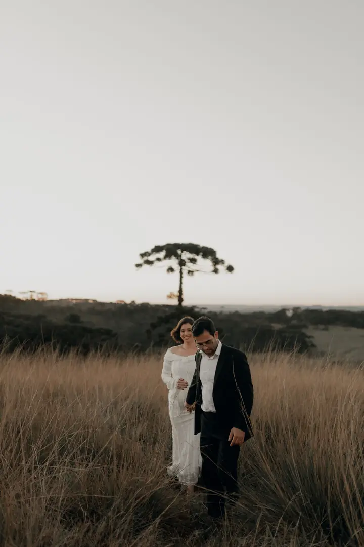 Casal no campo com uma araucária ao fundo