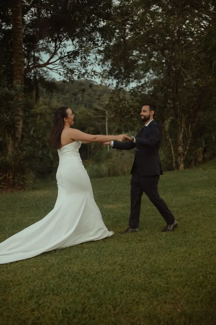 Casal dançando no gramado, a noiva girando o vestido